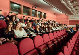 Uczniowie klas szóstych w sali teatralnej oczekują na rozpoczęcie spektaklu