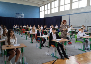 Ósmoklasiści na sali gimnastycznej przed rozpoczęciem egzaminu