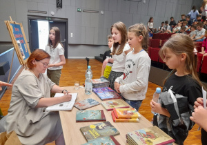 Uczniowie kupują książki z autografem pisarki